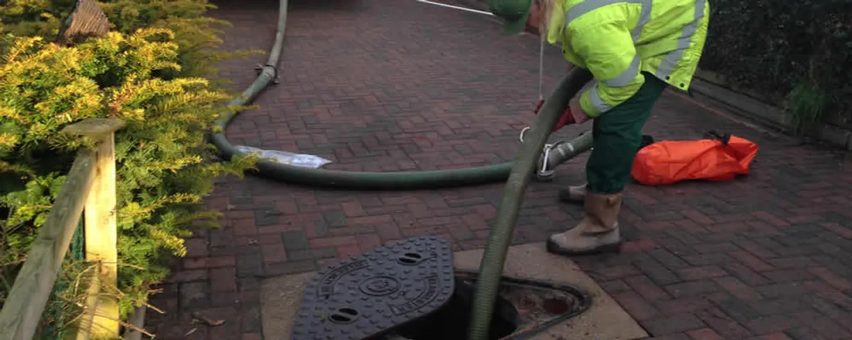 Septic tank cleaning technician servicing a septic tank with a vacuum hose in La Jolla, CA