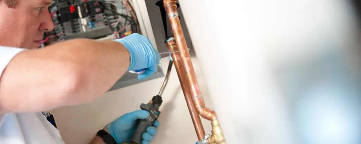 Water heater repair technician testing copper pipe connections and controls in La Jolla, CA